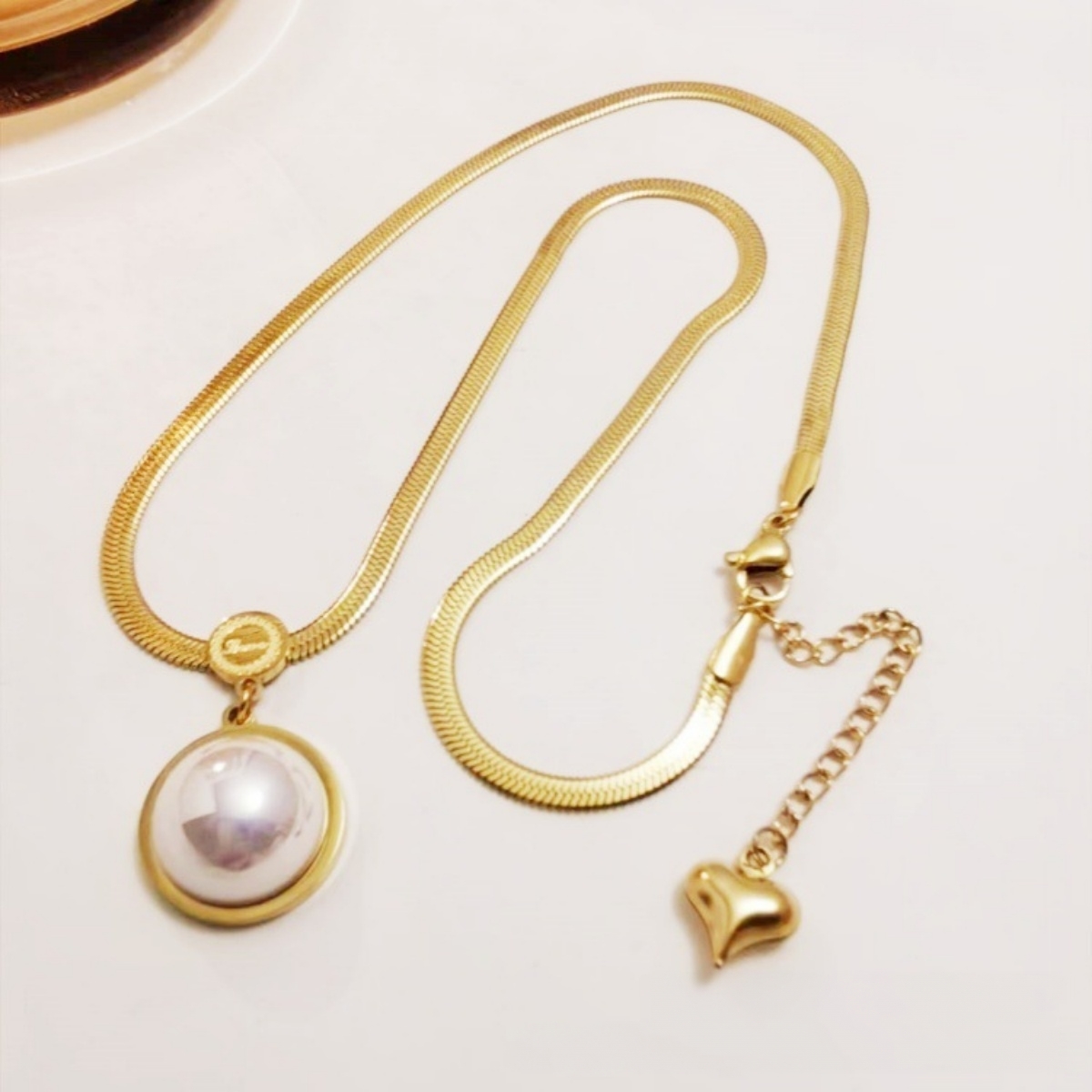 Pearl pendant snake chain necklace displayed in a light jewelry scene