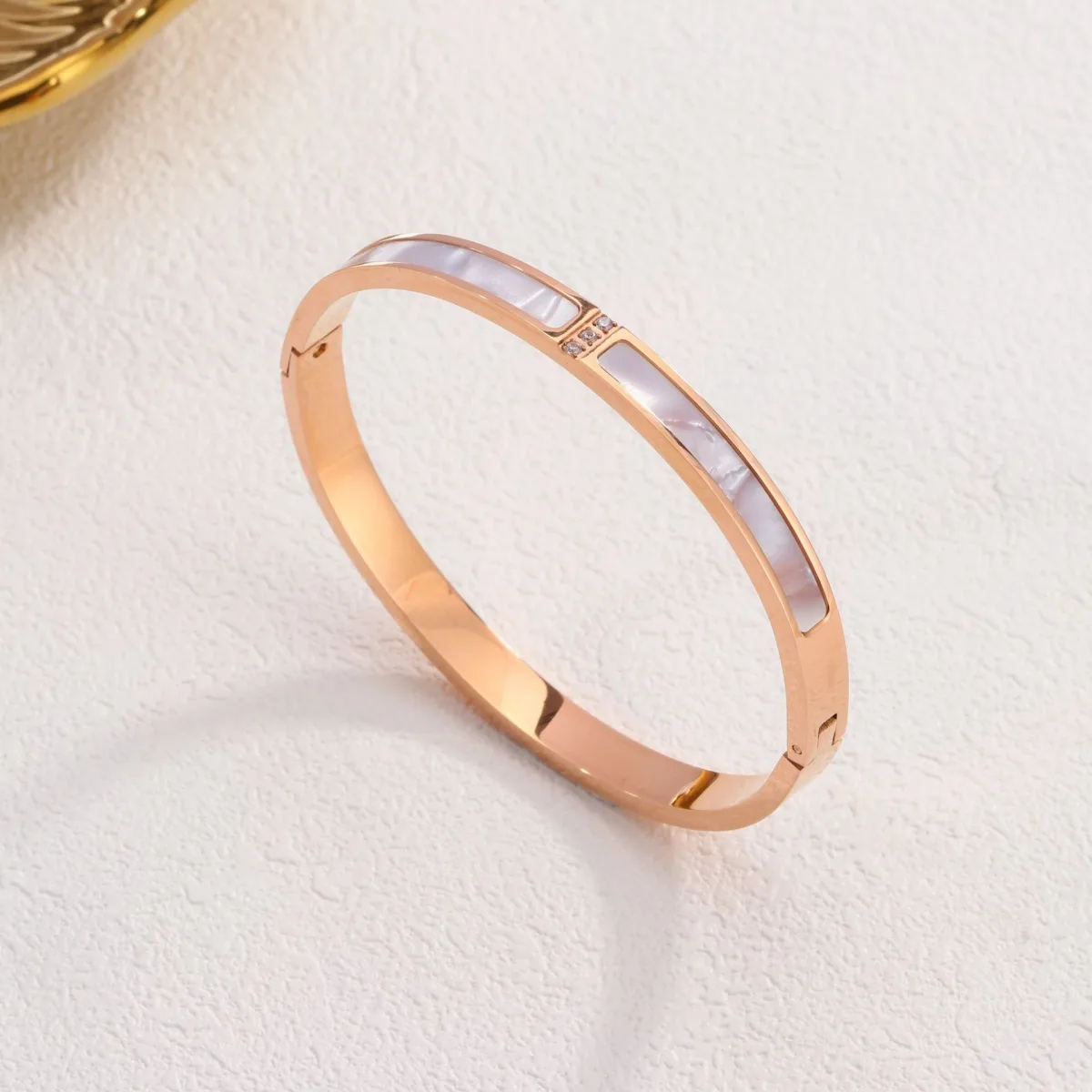 Gold stainless steel mother of pearl bangle on white background
