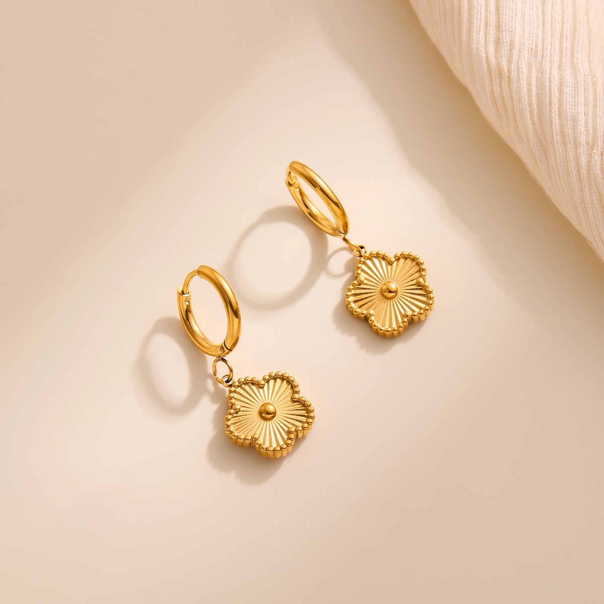 gold flower hoop earrings on white background