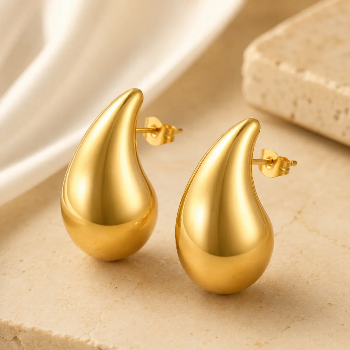 gold teardrop stud earrings on white background